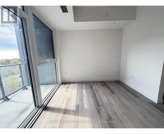 A room with a large window and wooden flooring.