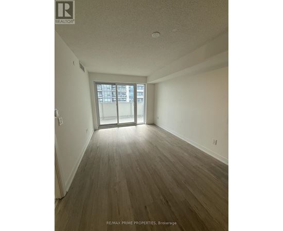 A room with wooden flooring and a sliding glass door leading to a balcony.