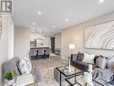 A modern living room with a grey sofa, a glass coffee table, and a large abstract painting on the wall.