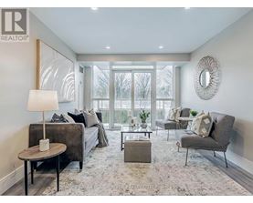 A well-lit, modern living room with a grey sofa, a grey armchair, a coffee table, and a round mirror on the wall.