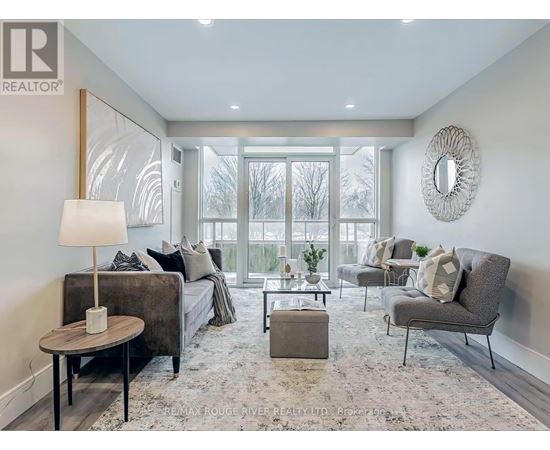 A well-lit, modern living room with a grey sofa, a grey armchair, a coffee table, and a round mirror on the wall.