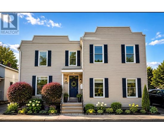 A two-story house with a blue door and black shutters is for sale.