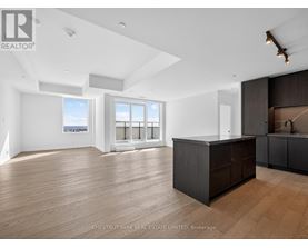 A spacious room with wooden flooring and a large island in the middle.