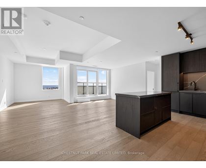 A spacious room with wooden flooring and a large island in the middle.