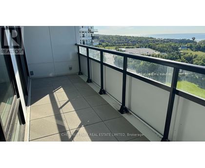 A balcony with a view of a parking lot and trees.