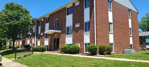 A red brick building with white trim and a white awning.