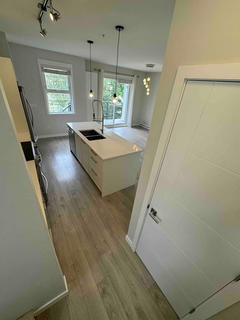 A kitchen with a white counter top and wooden floors.