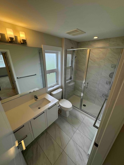 A bathroom with a toilet, sink, and shower.
