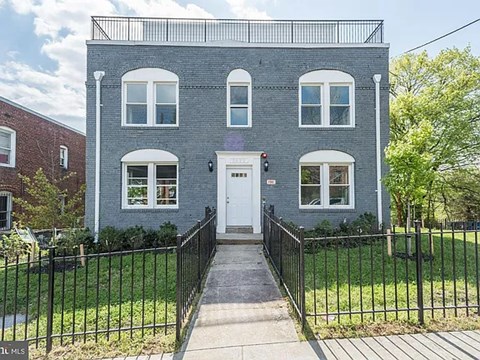 A grey two-story house with a white door and windows.