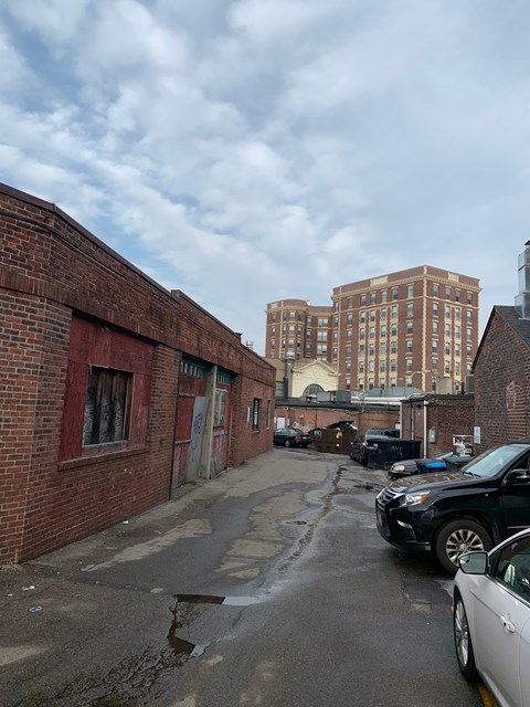 A brick building with a red door and a white car parked in front.