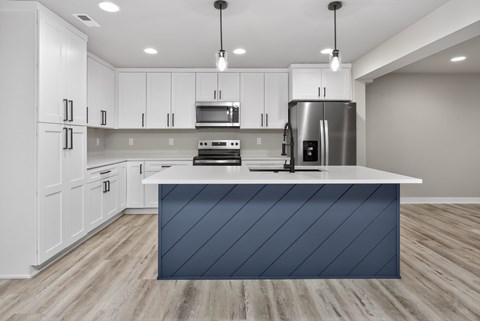 A modern kitchen with white cabinets and a dark blue island.