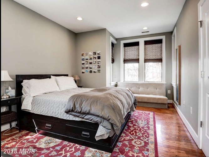 A bedroom with a large bed and a couch in the background.
