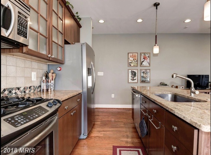 A kitchen with a stove top oven, microwave, refrigerator, and sink.