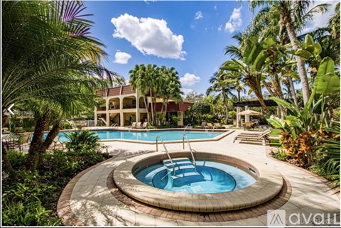 A round pool surrounded by palm trees and a building in the background.