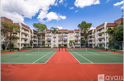 A tennis court in front of apartment buildings.
