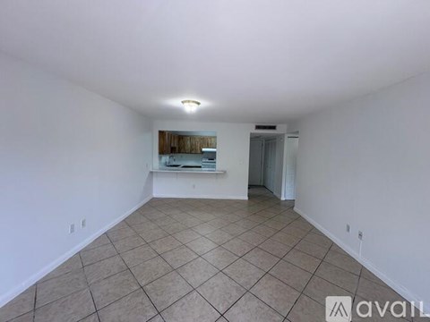 A spacious room with tiled flooring and white walls.
