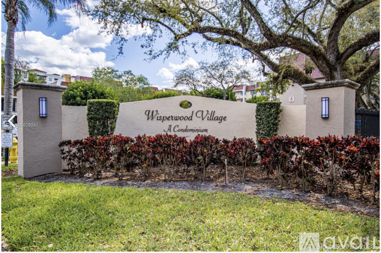 A sign that says "Weswood Village" is in front of a tree.