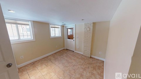 A room with beige walls and tiled flooring with a door and window.