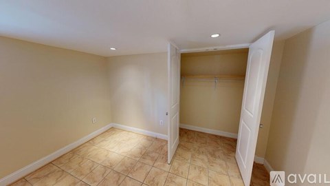 A room with beige walls and tiled flooring, featuring a closet with white doors.