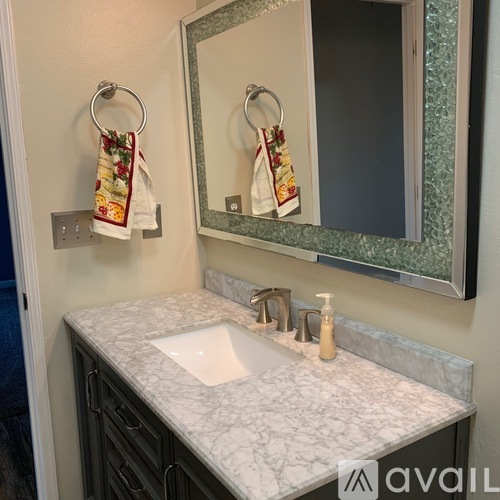 A bathroom with a marble countertop and a mirror above it.