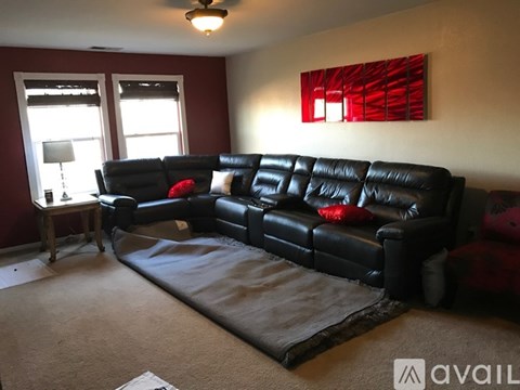A black leather couch with red pillows in a living room.