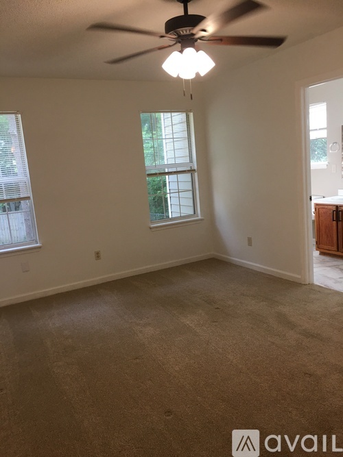A room with a ceiling fan and carpeted floor.