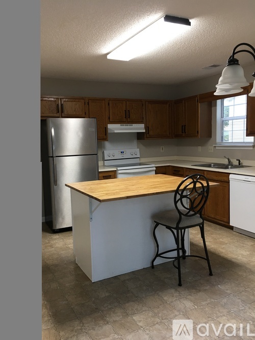 A kitchen with a wooden island and a refrigerator.