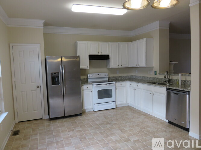A kitchen with white cabinets and a tile floor.