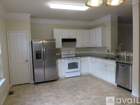 A kitchen with white cabinets and a tile floor.