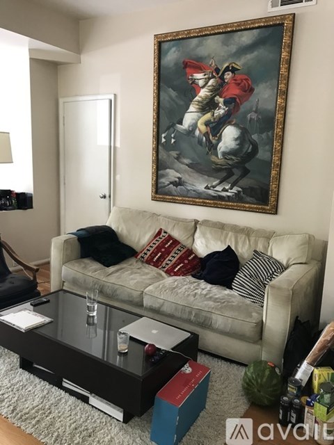 A living room with a couch, coffee table, and a painting on the wall.