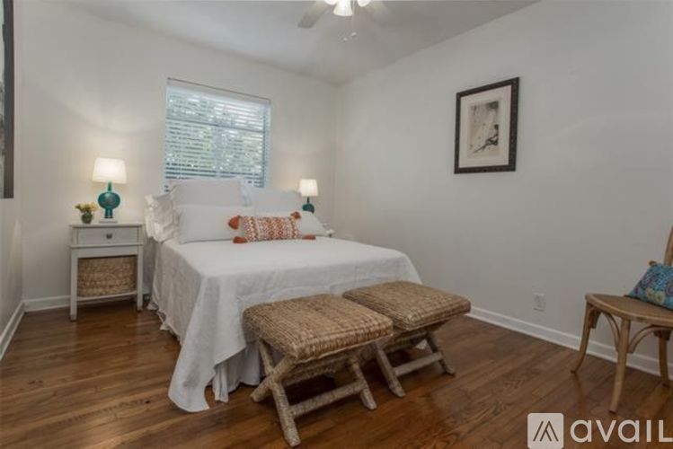 A bedroom with a bed, two lamps, a nightstand, and a chair.