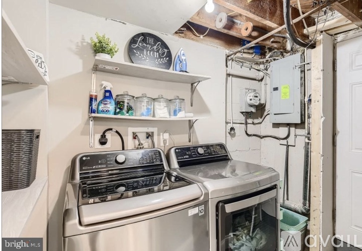A kitchen with a stove and oven, a shelf with cleaning supplies, and a white door.