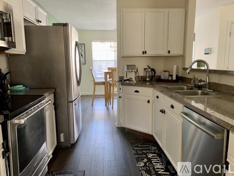 A kitchen with white cabinets and a black refrigerator.