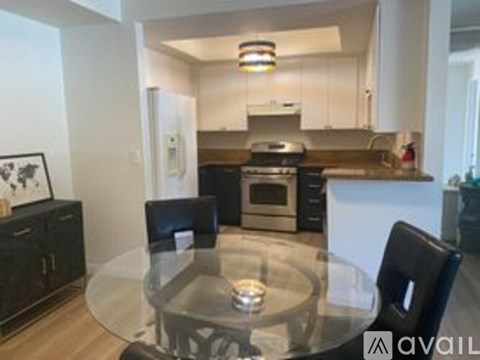 A modern kitchen with a glass table and black chairs.