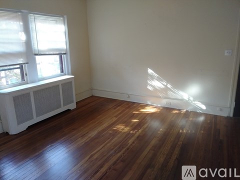 A room with wooden floors and a window with blinds.