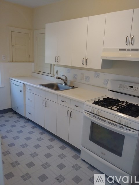 A kitchen with white cabinets and a checkered floor.