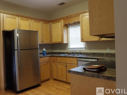 A kitchen with wooden cabinets and a stainless steel refrigerator.