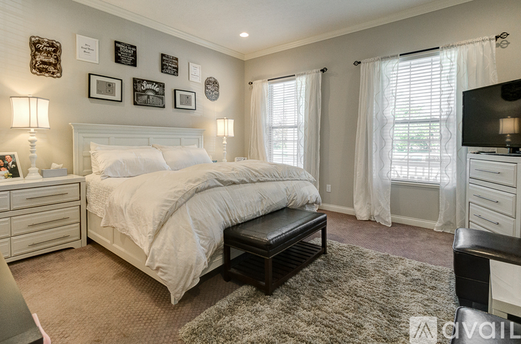 A bedroom with a large bed, a bench, and a television.