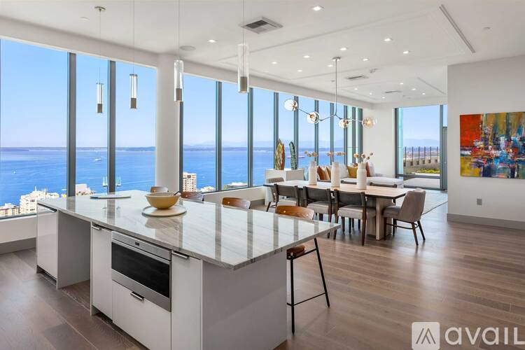 A modern kitchen with a large island and a dining table with chairs.