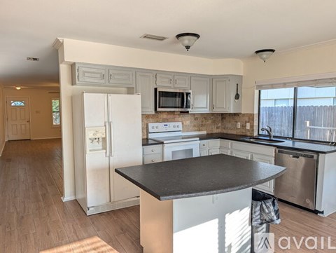 A kitchen with a refrigerator, microwave, oven, and sink.