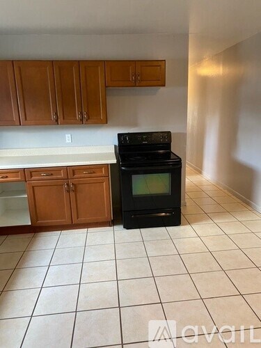 A kitchen with a black stove top oven and wooden cabinets.