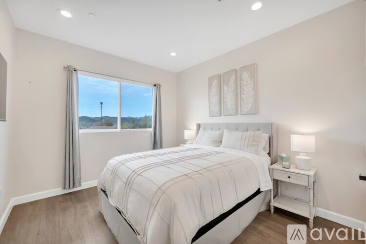 A bedroom with a large bed and a window overlooking a landscape.