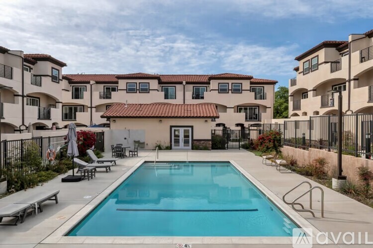 A swimming pool in front of a building with a fence around it.