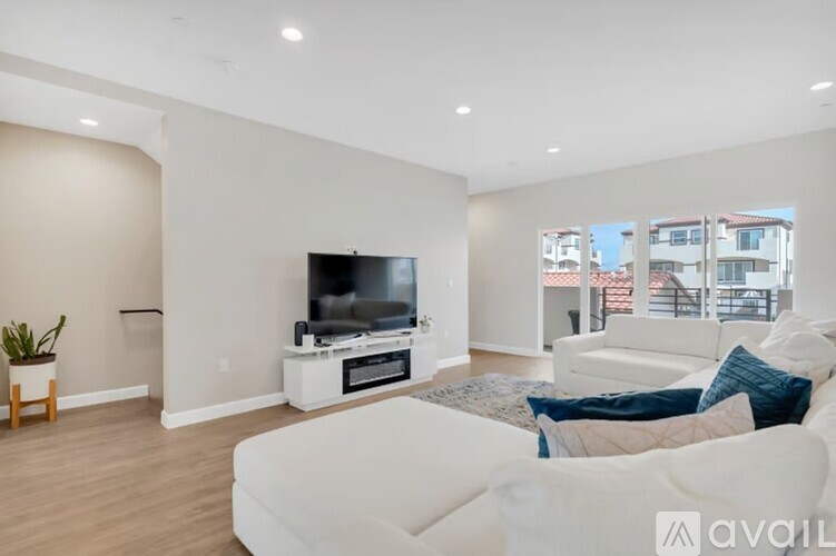 A living room with a white couch and a television on a white stand.