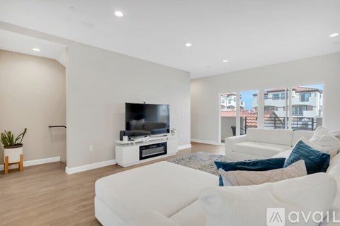 A living room with a white couch and a television on a white stand.
