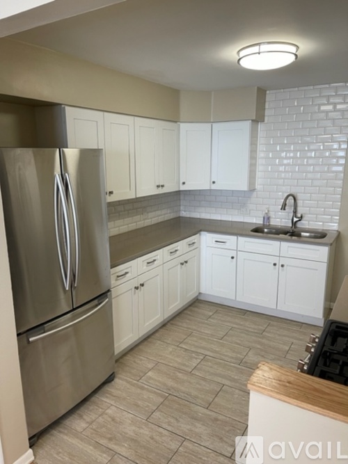 A kitchen with a stainless steel refrigerator and white cabinets.