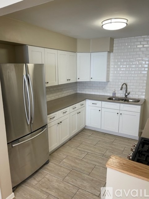 A kitchen with a stainless steel refrigerator and white cabinets.