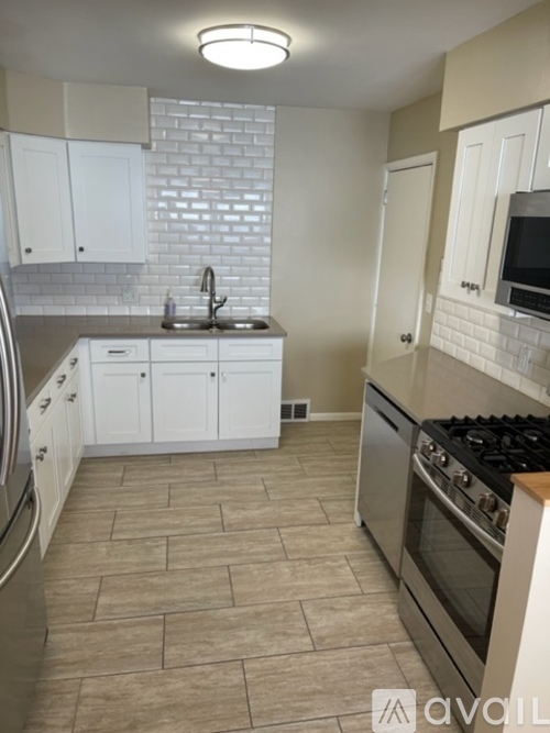 A kitchen with white cabinets and a tiled backsplash.