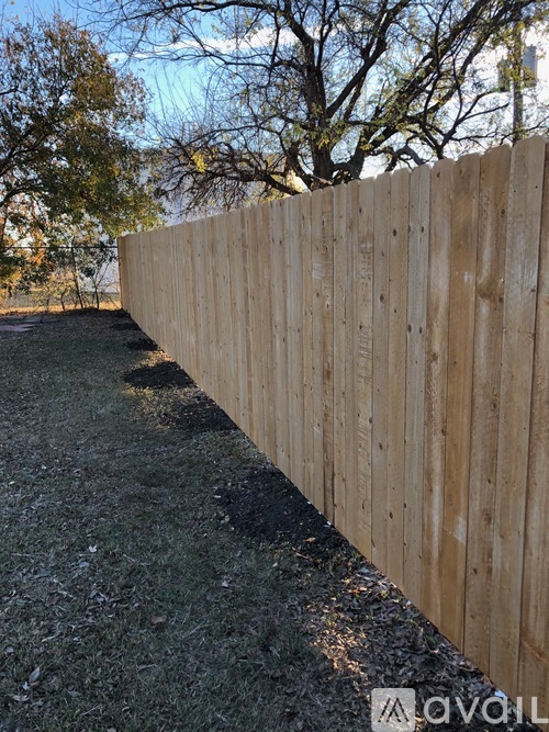 A wooden fence runs along a grassy area.