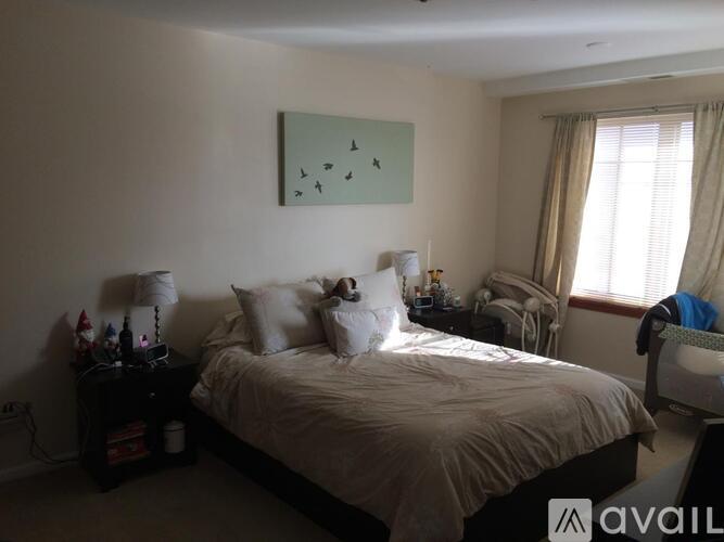 A bedroom with a bed, a chair, and a painting on the wall.